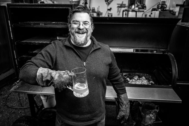 BeefStew — pitmaster, beer in hand, grinning next to Baby